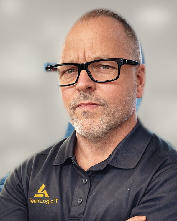 Don Zurbrick in a dark TeamLogic IT polo shirt and black glasses